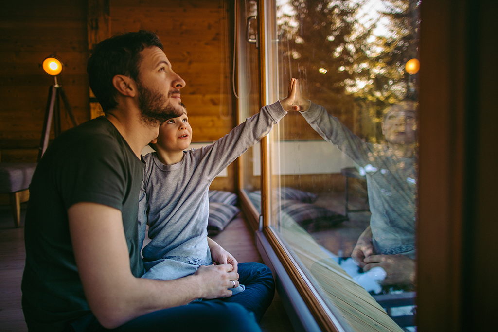 father and son looking out window